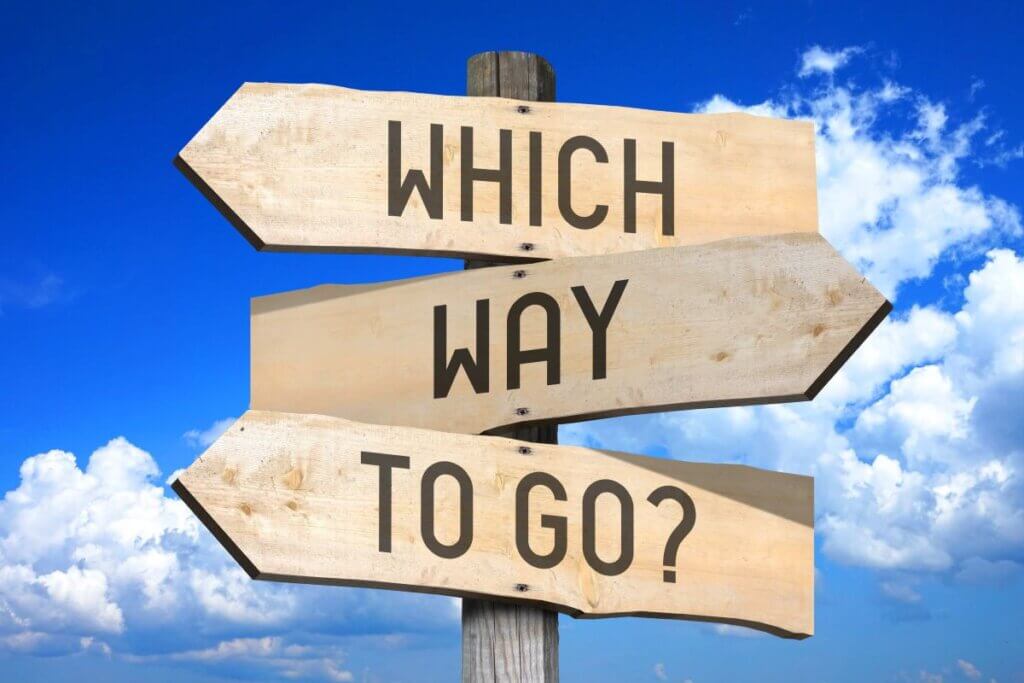 Wooden plank sign saying which way to go with planks pointed in different directions